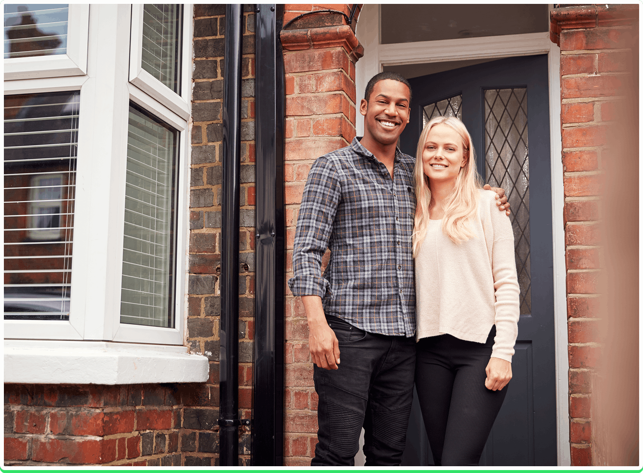 Happy smiling couple standing outside their home, the background showing freshly renovated windows and a new door