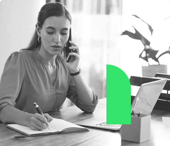 Sales rep at desk on the phone speaking to a qualified appointment lead while writing down notes