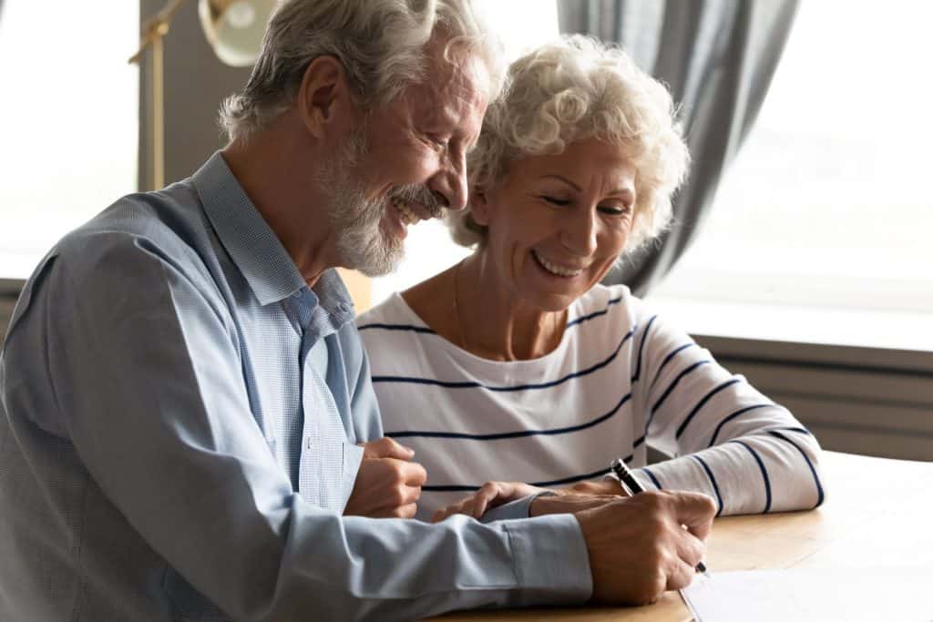 Smiling elderly couple at home signing a home improvement contract